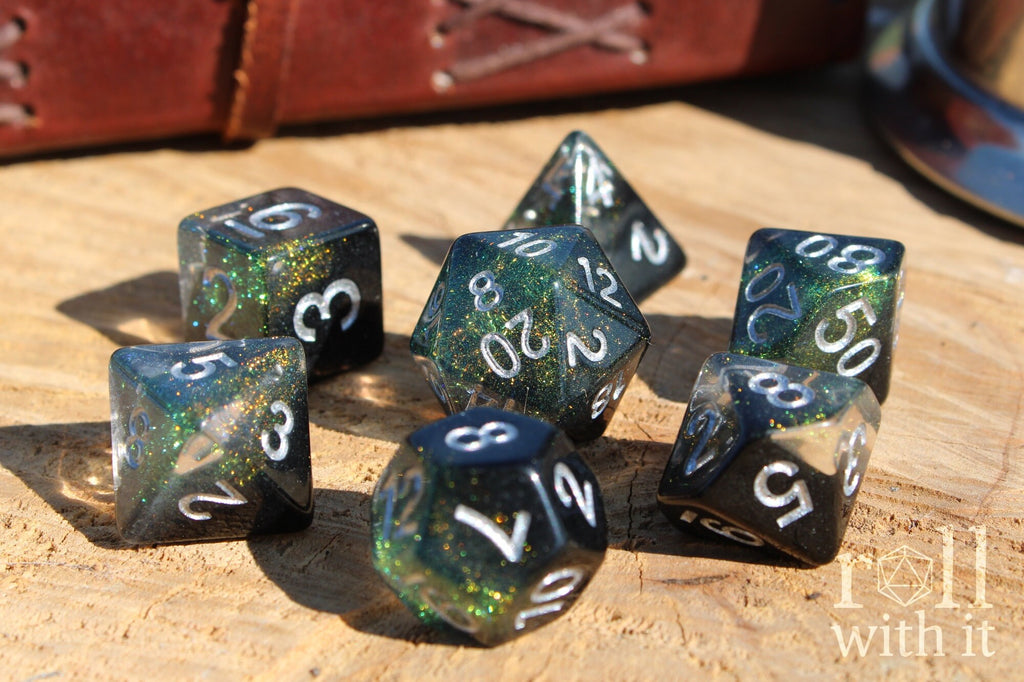 Set of glittery black and starry galaxy like polyhedral dice on a wooden surface