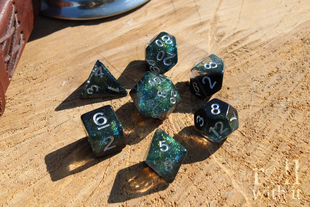 Set of glittery black and starry galaxy like polyhedral dice on a wooden surface