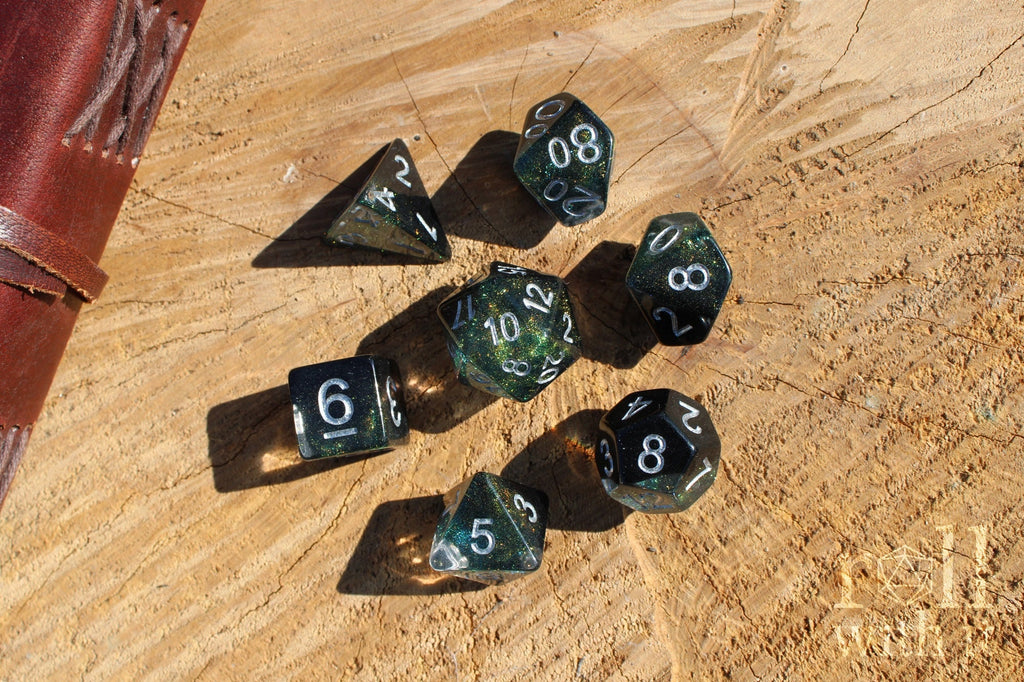 Set of glittery black and starry galaxy like polyhedral dice on a wooden surface