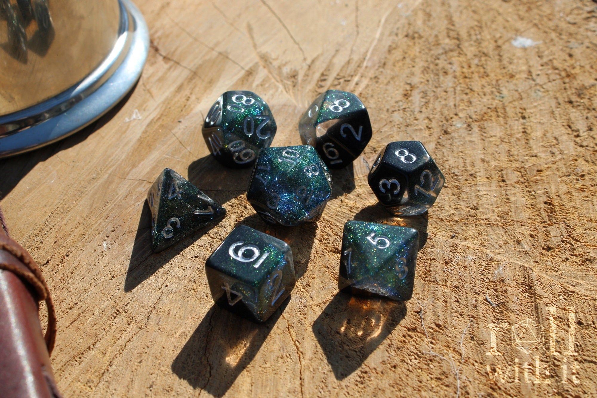 Set of glittery black and starry galaxy like polyhedral dice on a wooden surface
