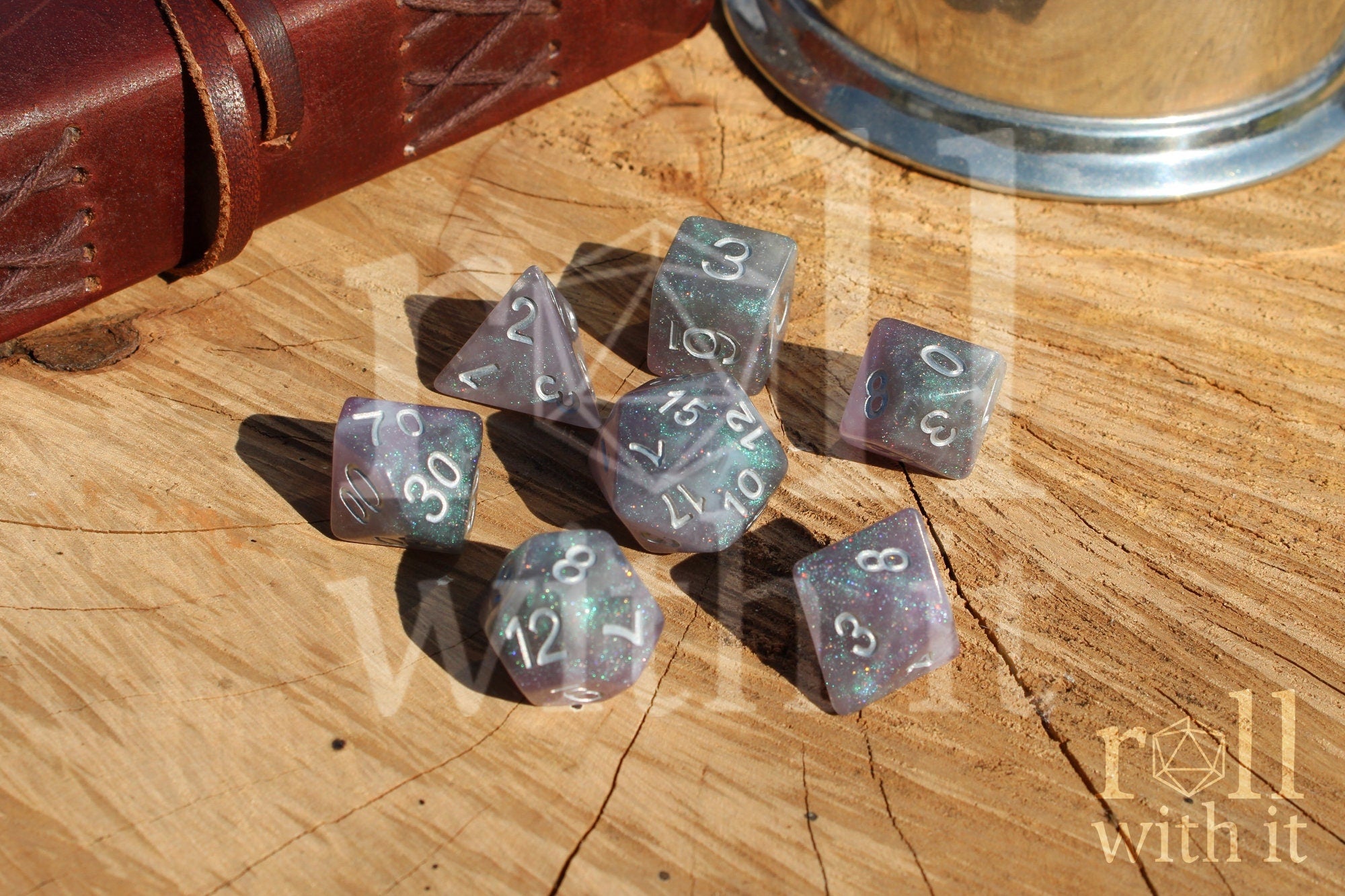 Set of silver and glittery polyhedral dice with numbers on a wooden surface