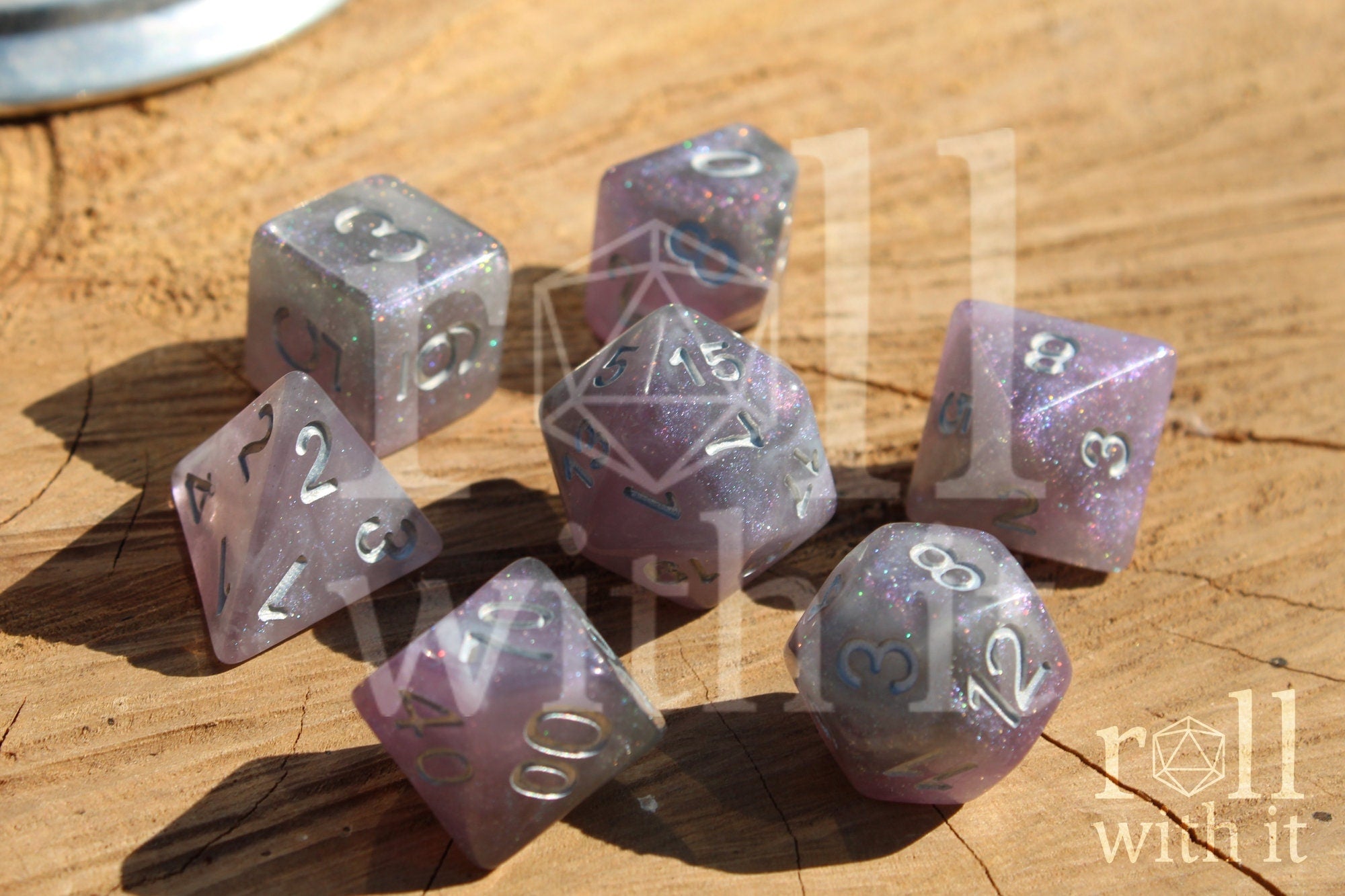 Set of silver and violet glittery polyhedral roleplaying dice with numbers on a wooden surface