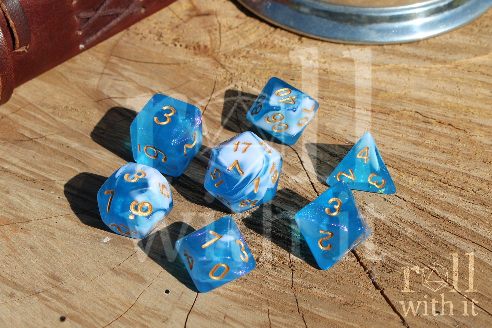 Set of blue and white glittery polyhedral dice with gold numbers on a wooden surface