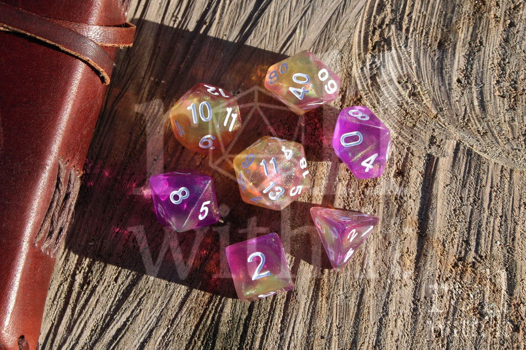 Set of colourful purple pink and yellow glittery polyhedral DnD dice on a wooden surface