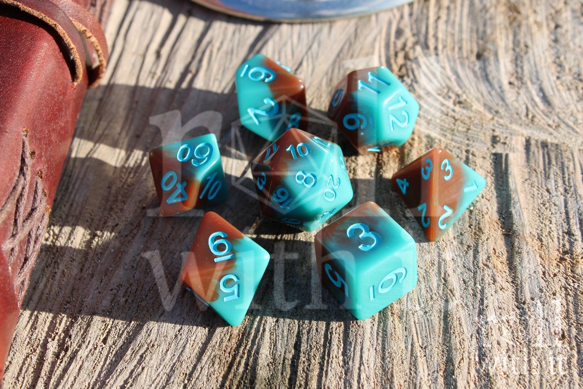 Set of turquoise blue and chocolate brown polyhedral roleplaying dice on a wooden surface