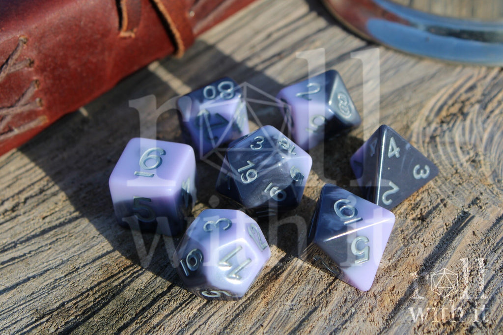 Set of pale lilac, purple and grey swirling  polyhedral roleplaying dice on a wooden surface 