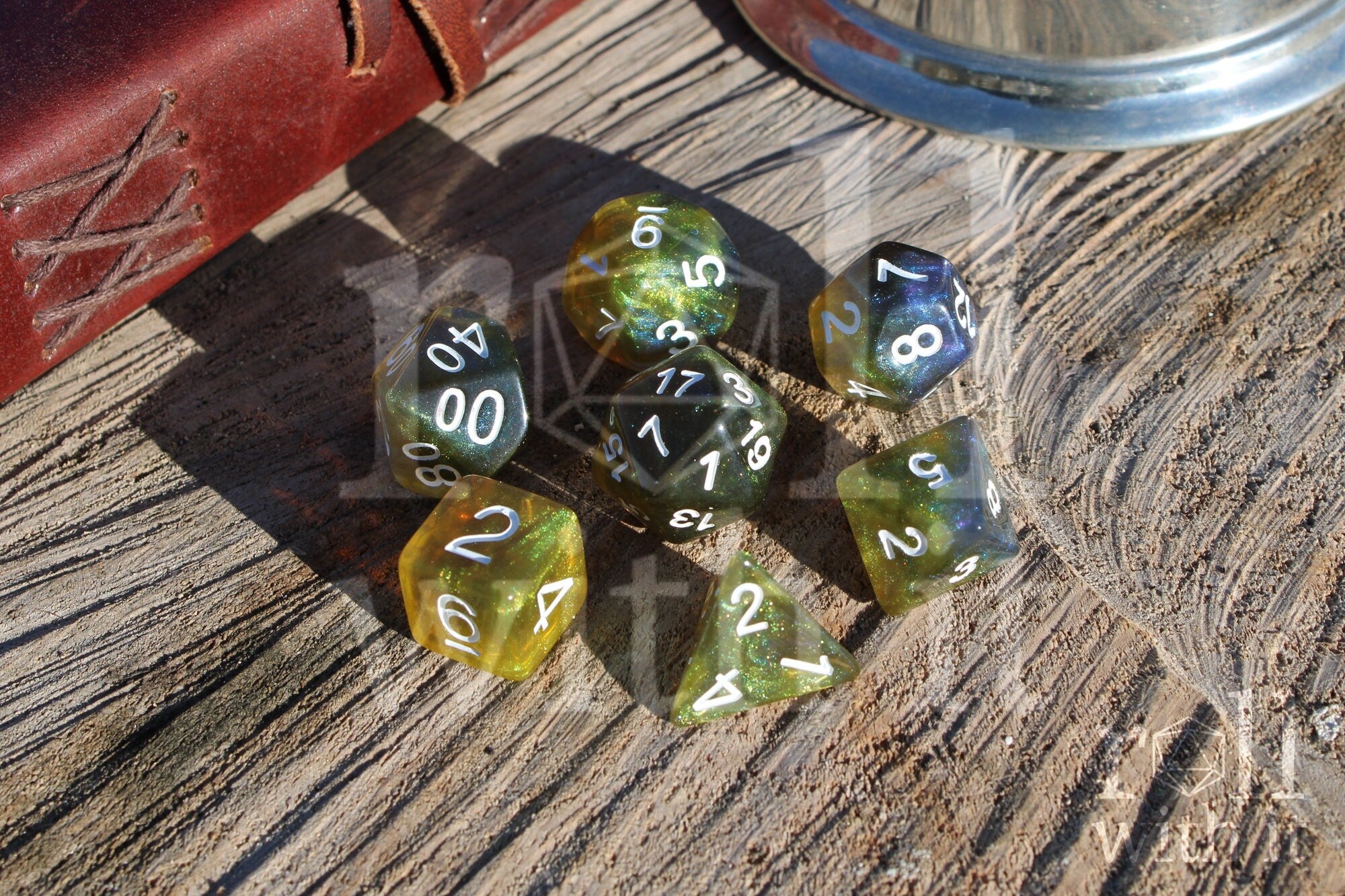 Set of green olive and blue polyhedral dice with white numbers on a wooden surface.