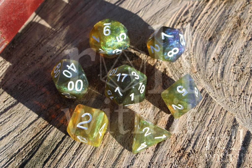 Set of green olive and blue polyhedral dice with white numbers on a wooden surface.