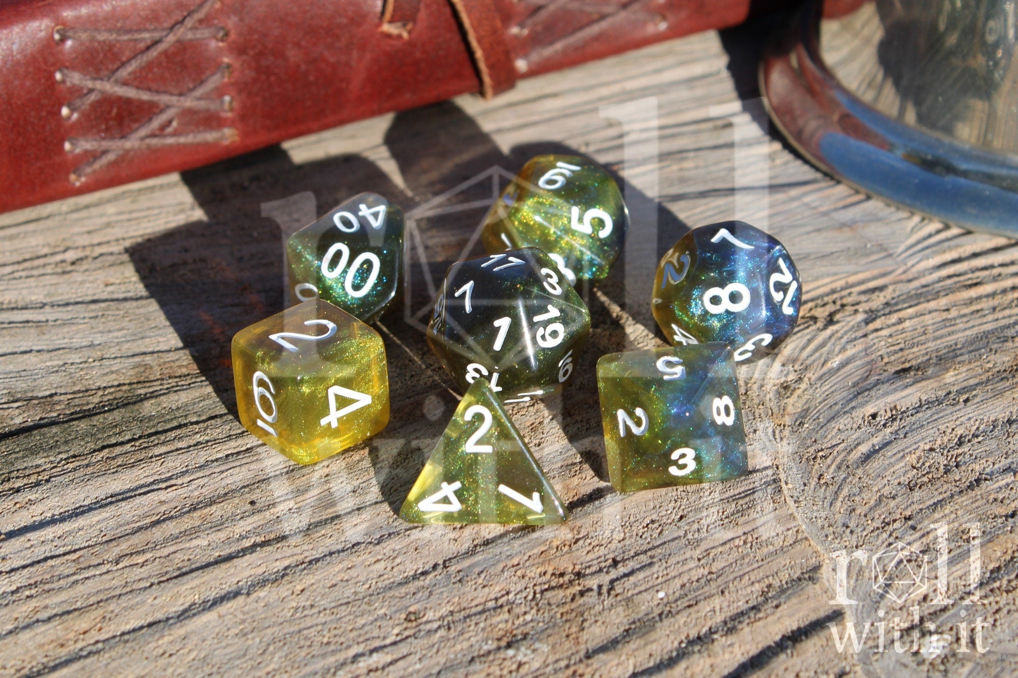 Set of green olive and blue polyhedral dice with white numbers on a wooden surface.