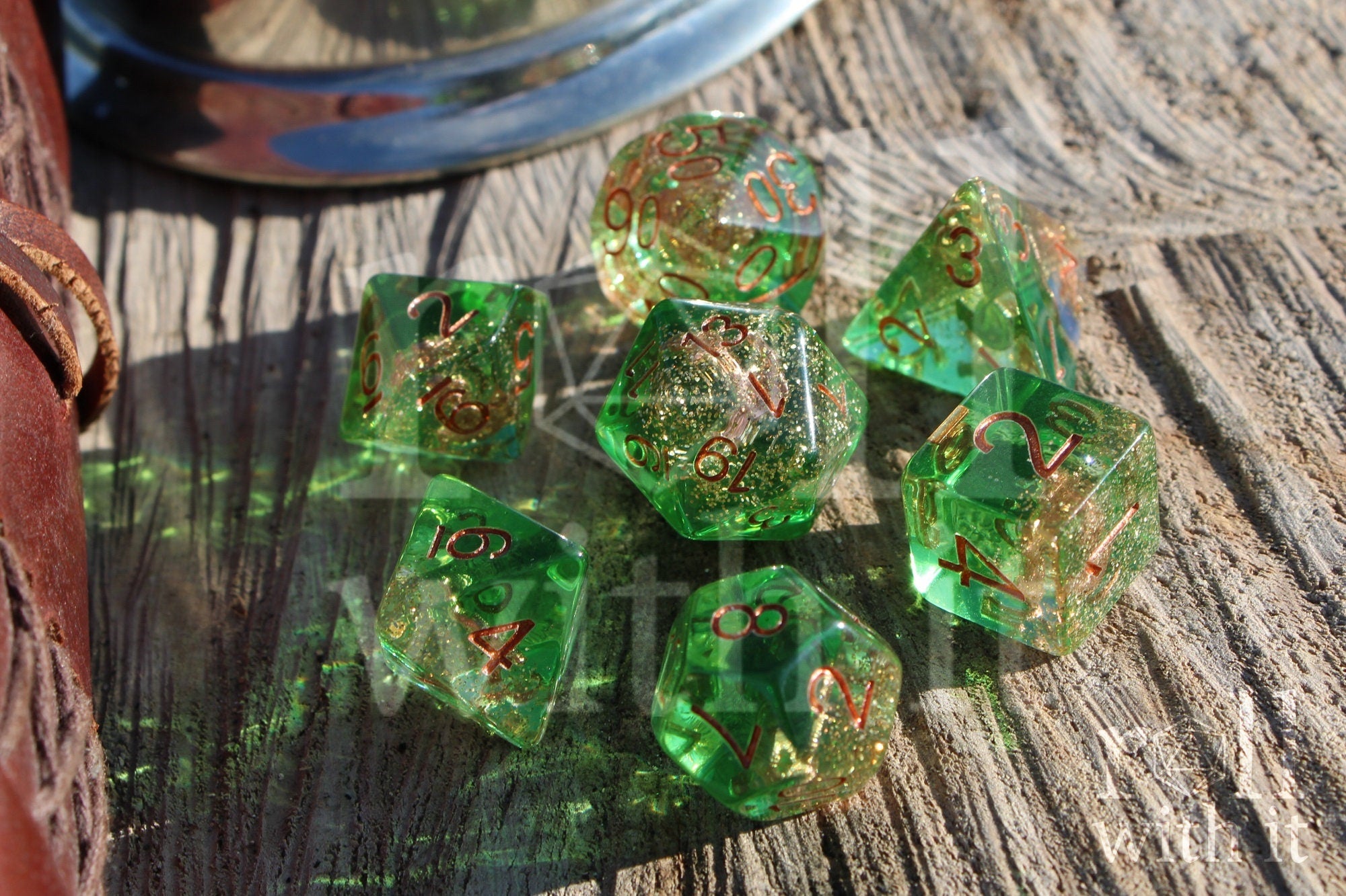 Set of green golden glittery dice with an anchor inside polyhedral dice with copper numbers on a wooden surface