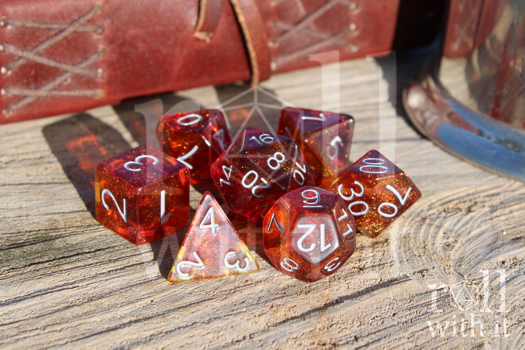Set of vibrant and glittery red and orange polyhedral DND dice with white numbers on a wooden surface