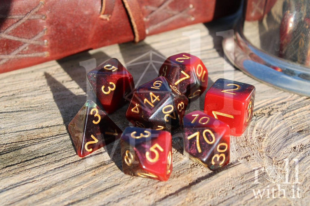 Set of colourful red and deep blue glittery polyhedral dice with gold numbers on a wooden surface