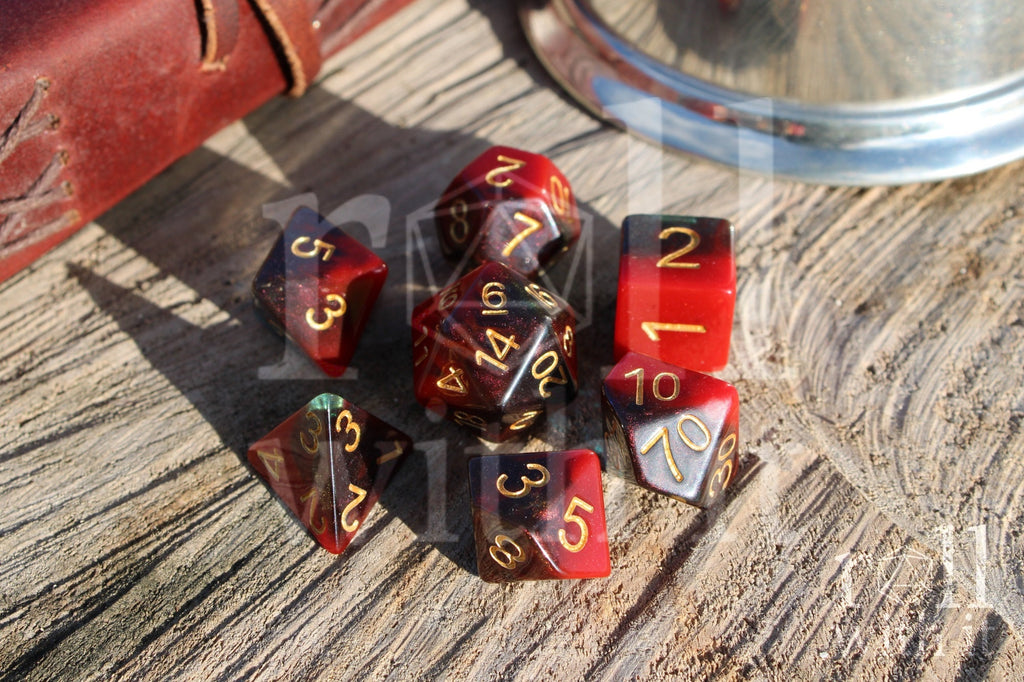 Set of colourful red and deep blue glittery polyhedral dice with gold numbers on a wooden surface