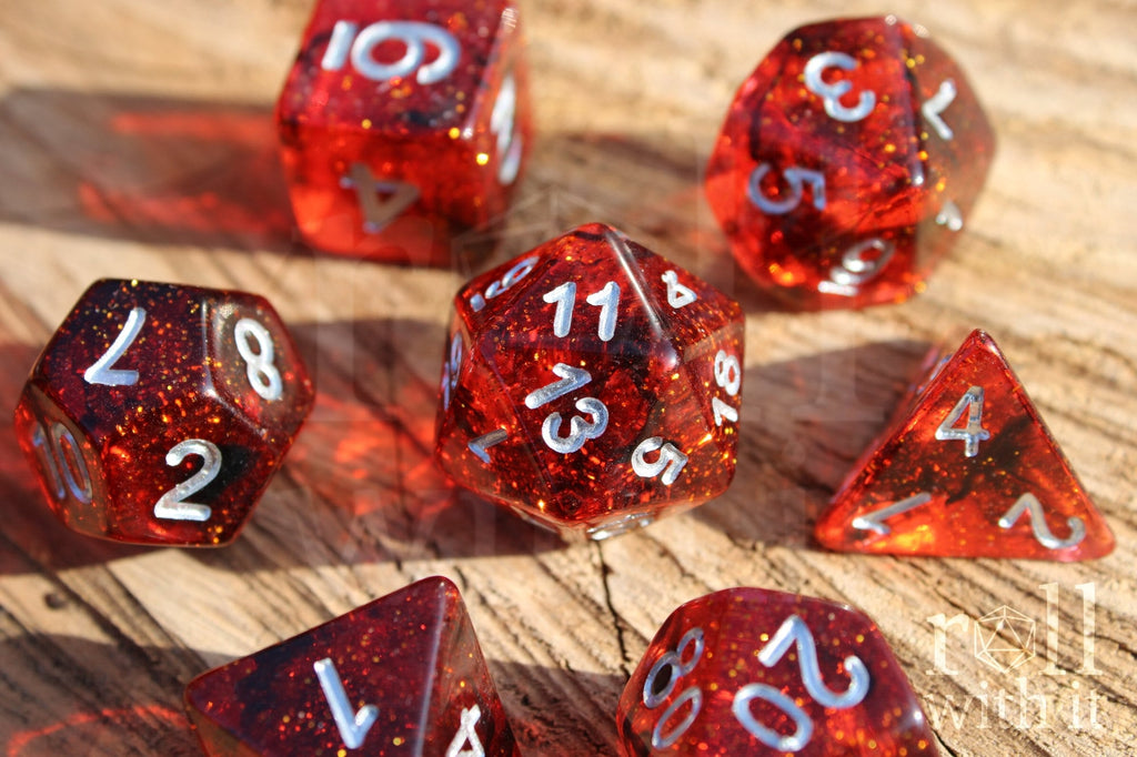 Set of red and black glittery polyhedral roleplaying dice with silver numbers on a wooden surface