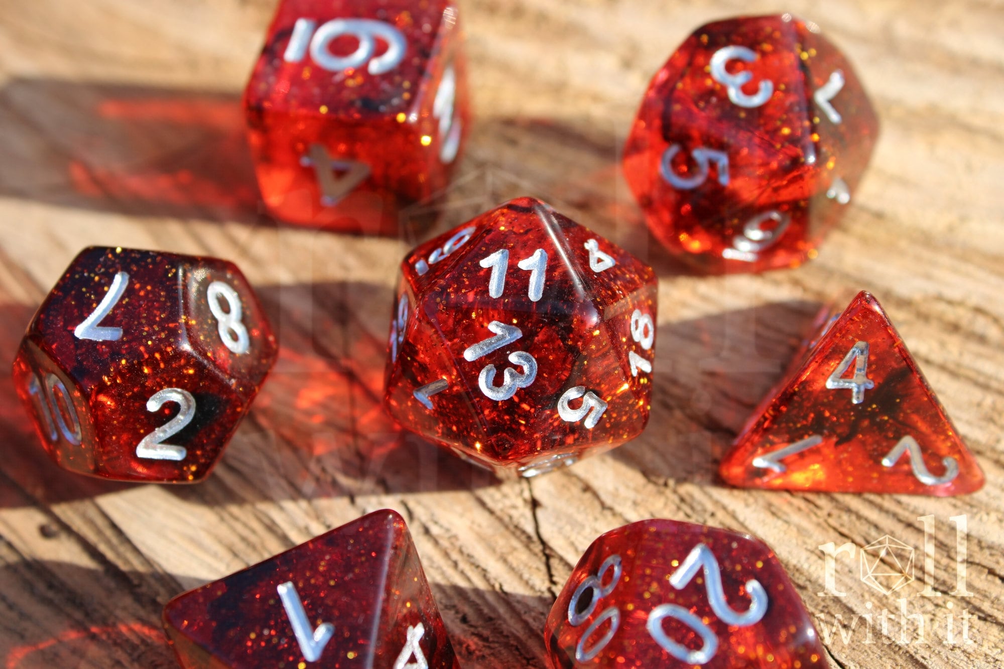 Set of red and black glittery polyhedral roleplaying dice with silver numbers on a wooden surface