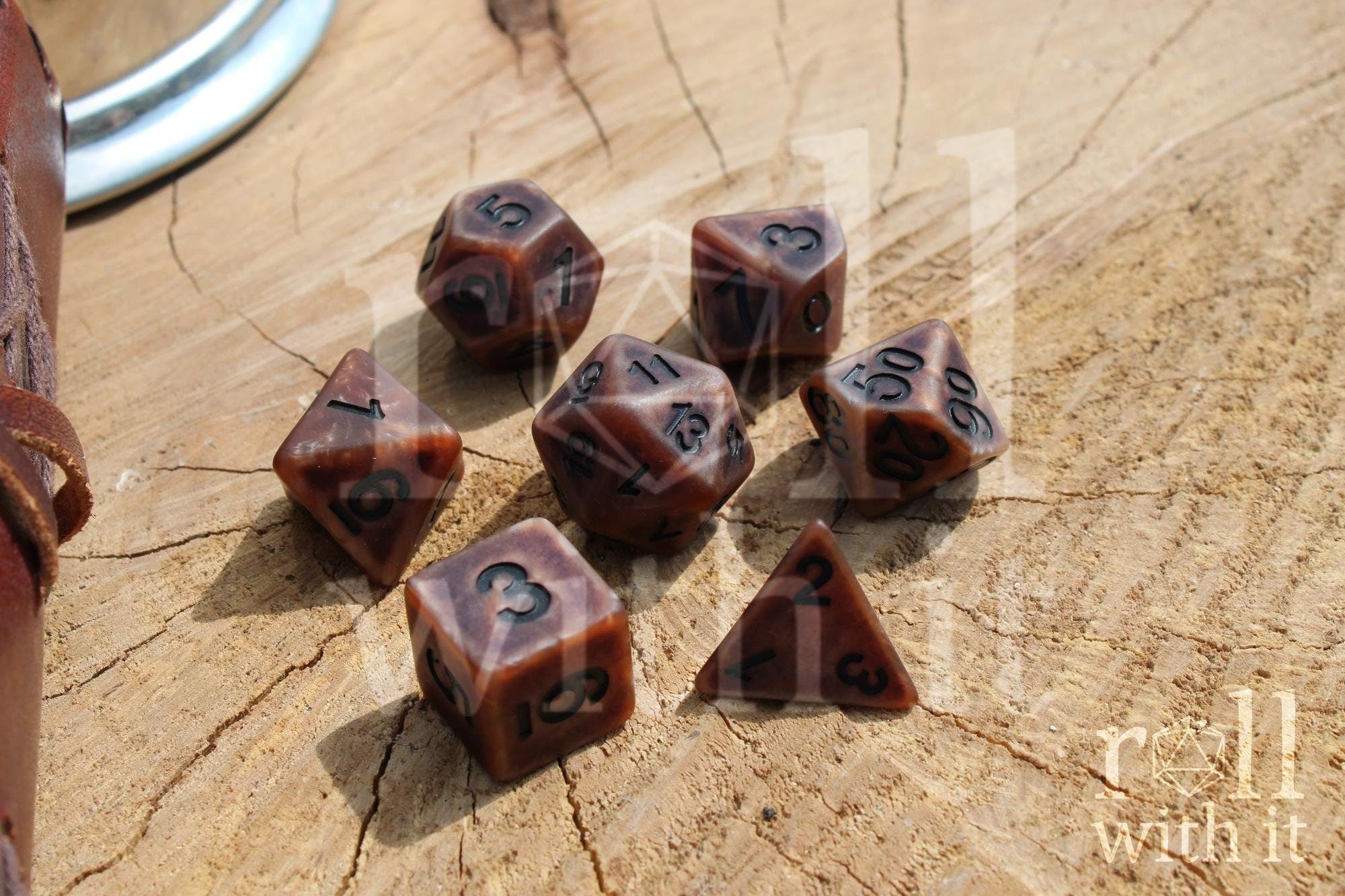 Set of rustic matte bronze copper polyhedral DnD roleplaying dice with black numbers on a wooden surface