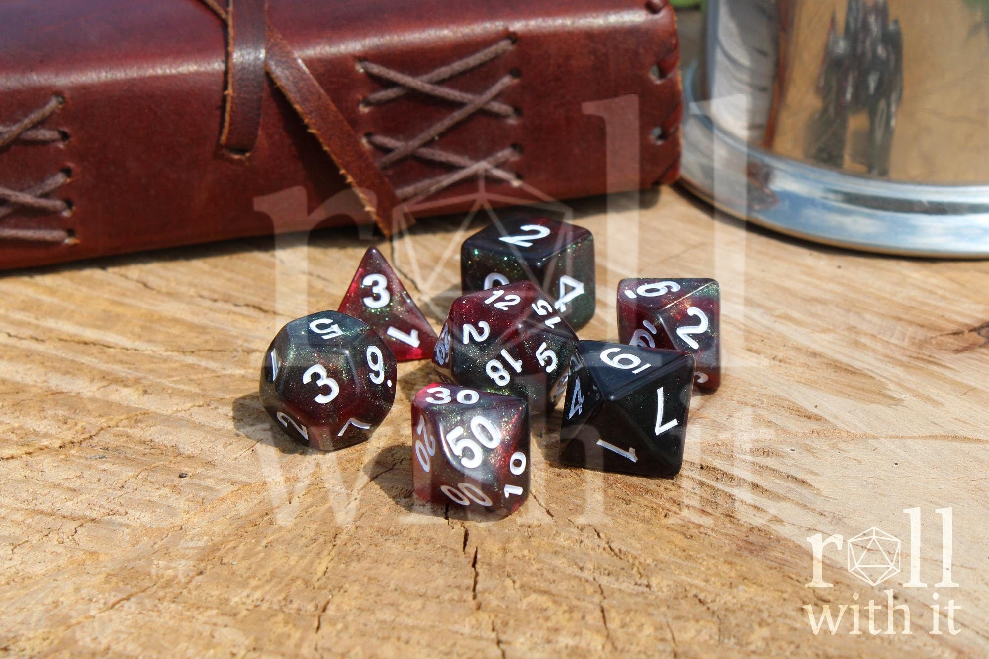 Set of glittery and star like black and red polyhedral dice with a green shimmer on a wooden surface