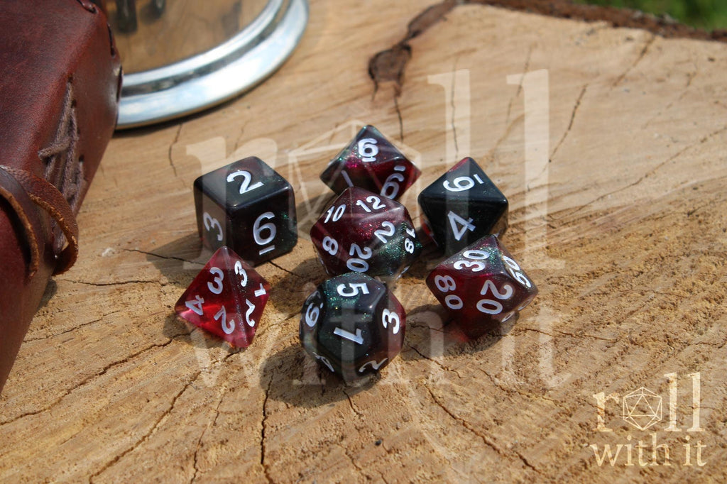 Set of glittery and star like black and red polyhedral dice with a green shimmer on a wooden surface