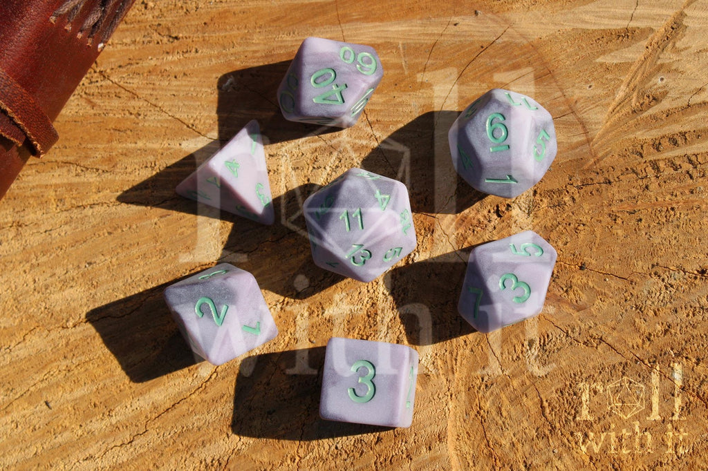 Lilac purple matte polyhedral DnD roleplaying dice with mint green numbers on a wooden surface