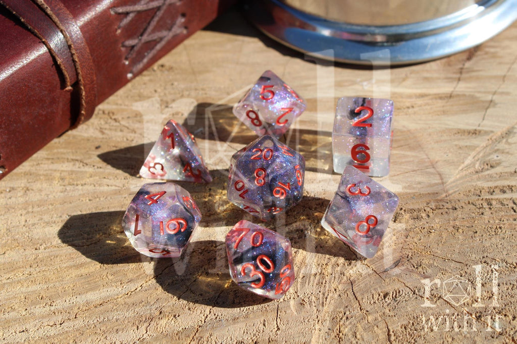 Transparent starry glittery purple and black dice with red numbers on a wooden surface