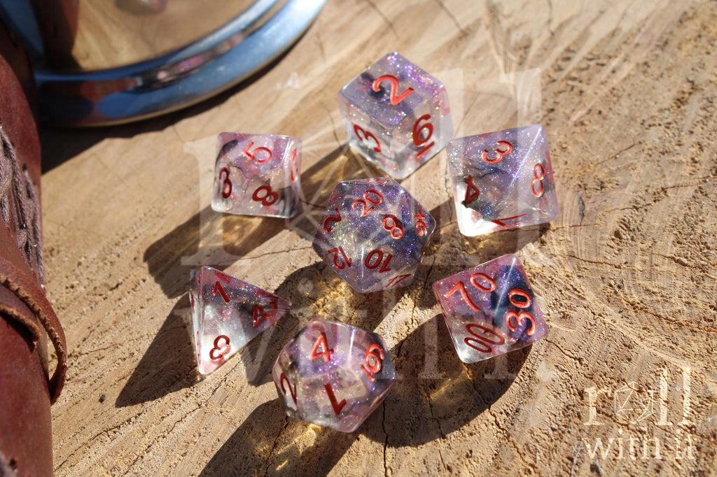 Transparent starry glittery purple and black dice with red numbers on a wooden surface