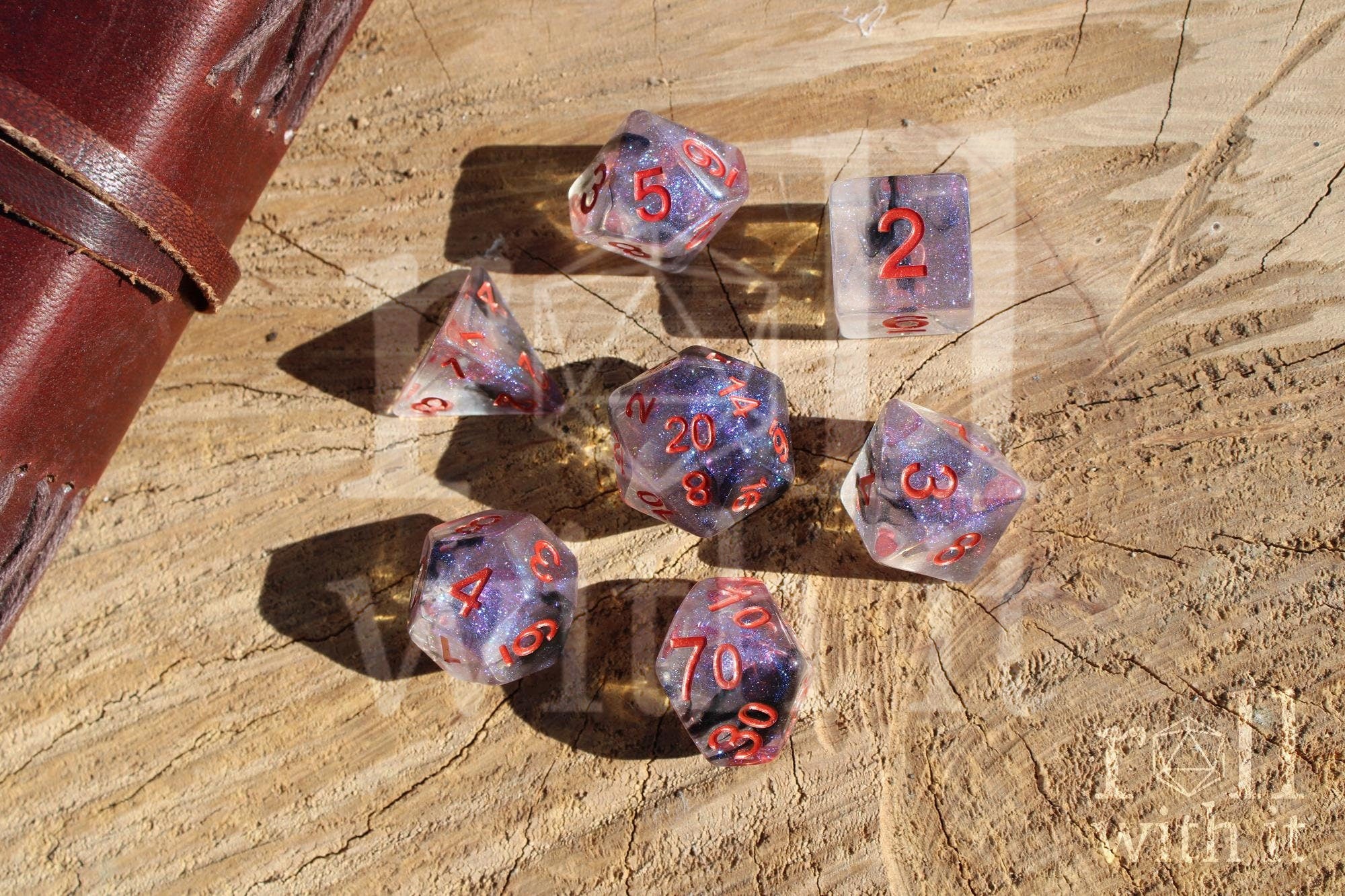 Transparent starry glittery purple and black roleplaying dice with red numbers on a wooden surface