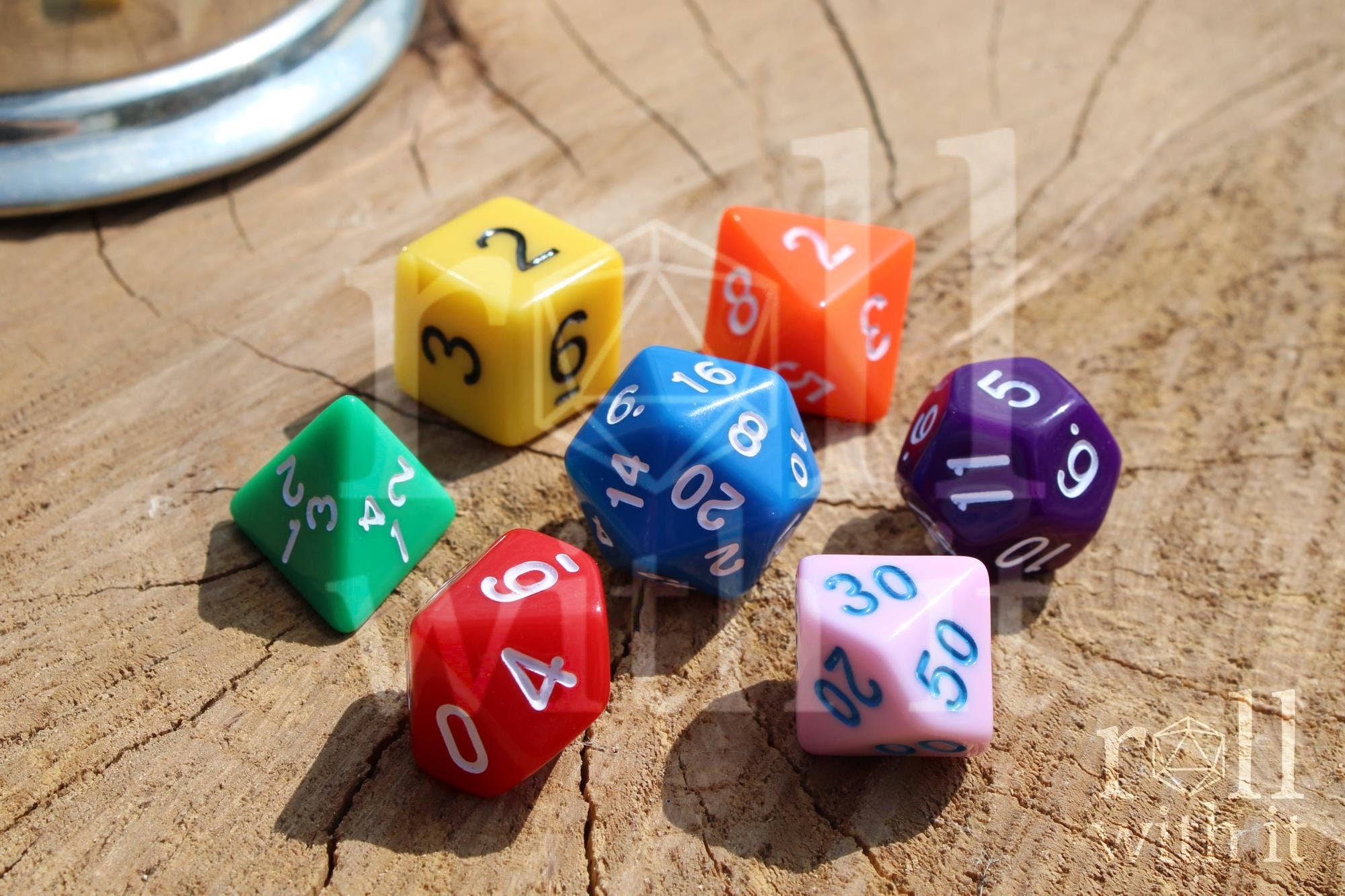 A colourful set of rainbow polyhedral roleplaying dice with white, blue, and black numbers on a wooden surface