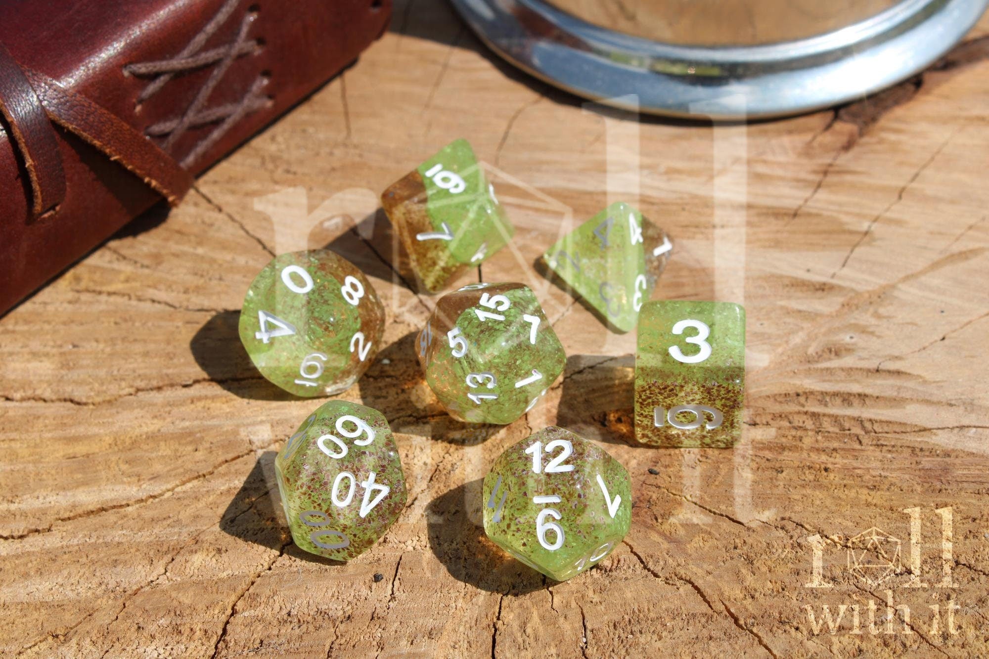 Translucent apple green and ginger brown speckled polyhedral roleplaying dice with white numbers on a wooden surface