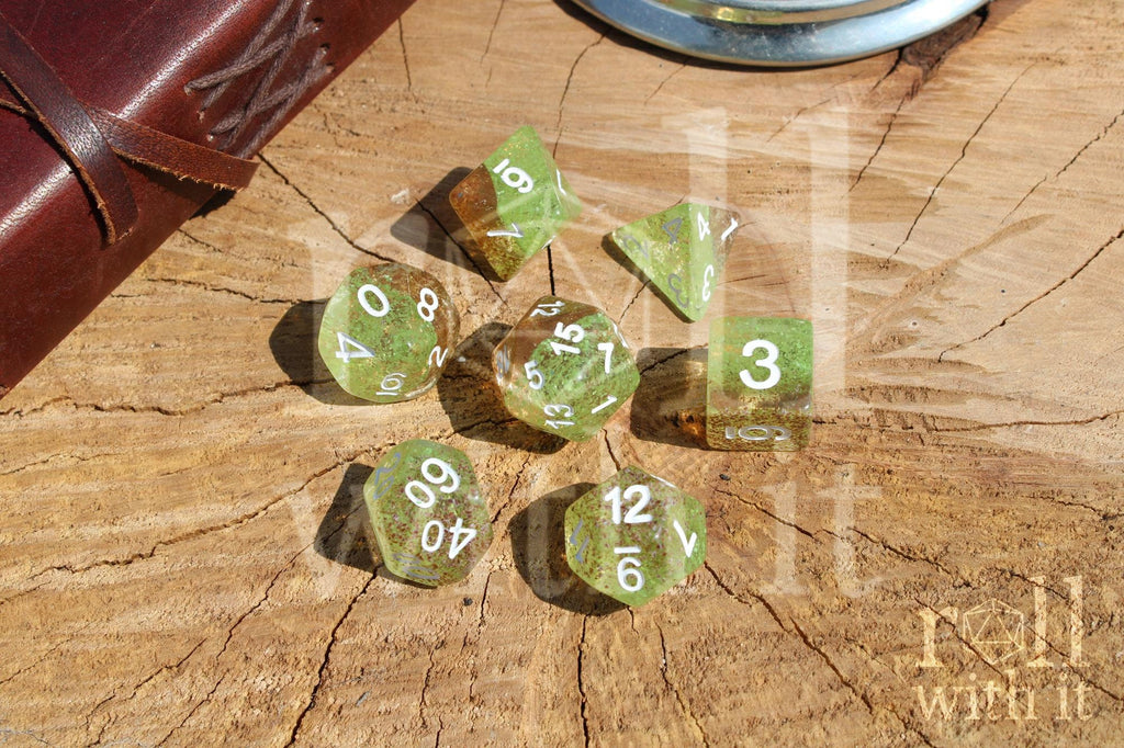Translucent apple green and ginger brown speckled polyhedral roleplaying dice with white numbers on a wooden surface