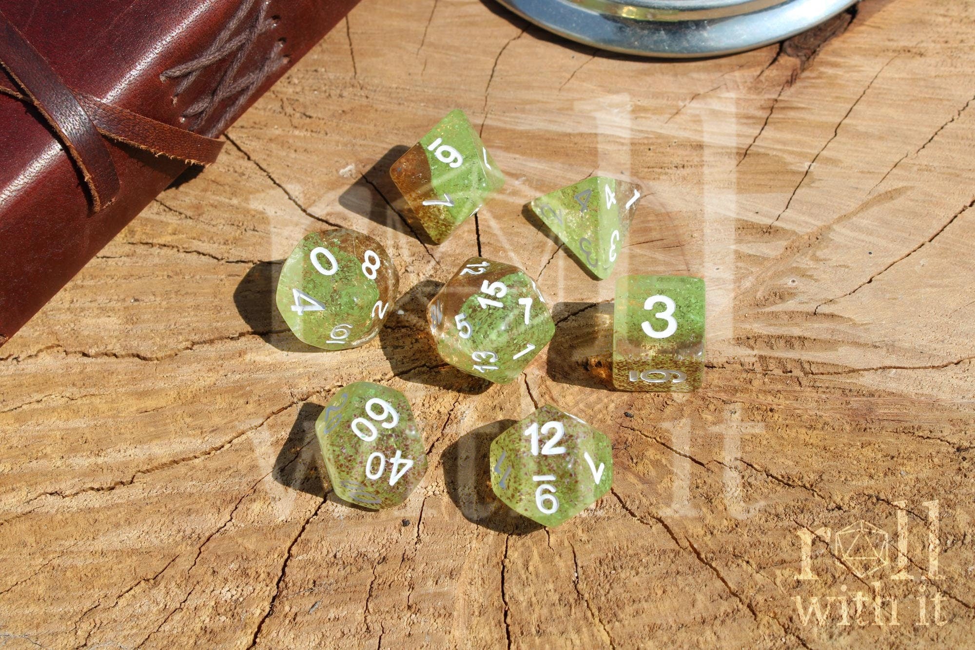 Translucent apple green and ginger brown speckled polyhedral roleplaying dice with white numbers on a wooden surface