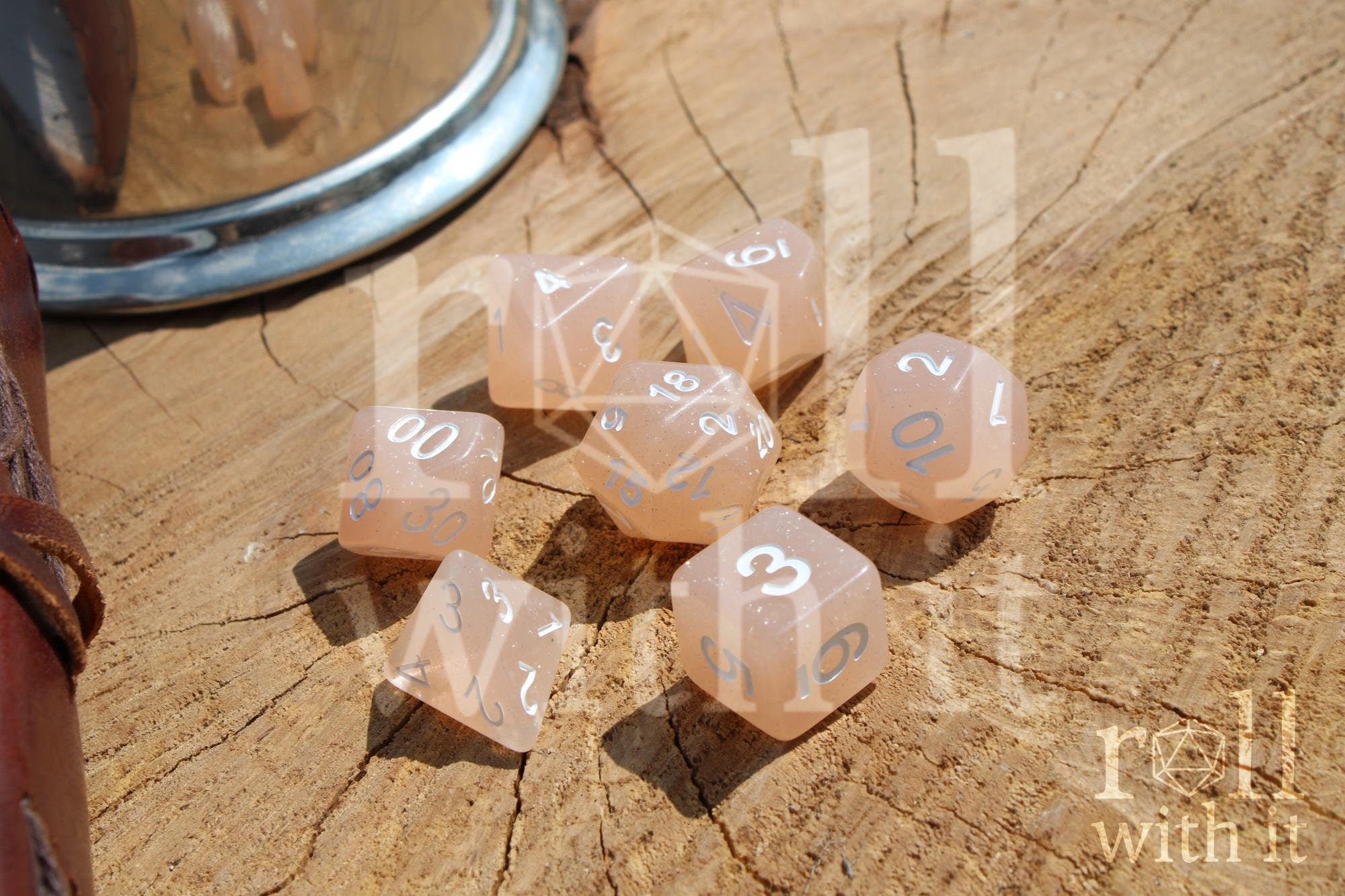 Set of creamy beige glittery polyhedral dice with white numbers on a wooden surface