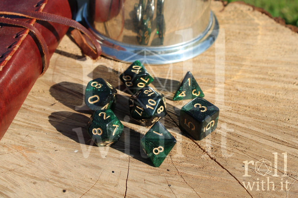 Set of starry green glittery polyhedral dice with gold numbers on a wooden surface
