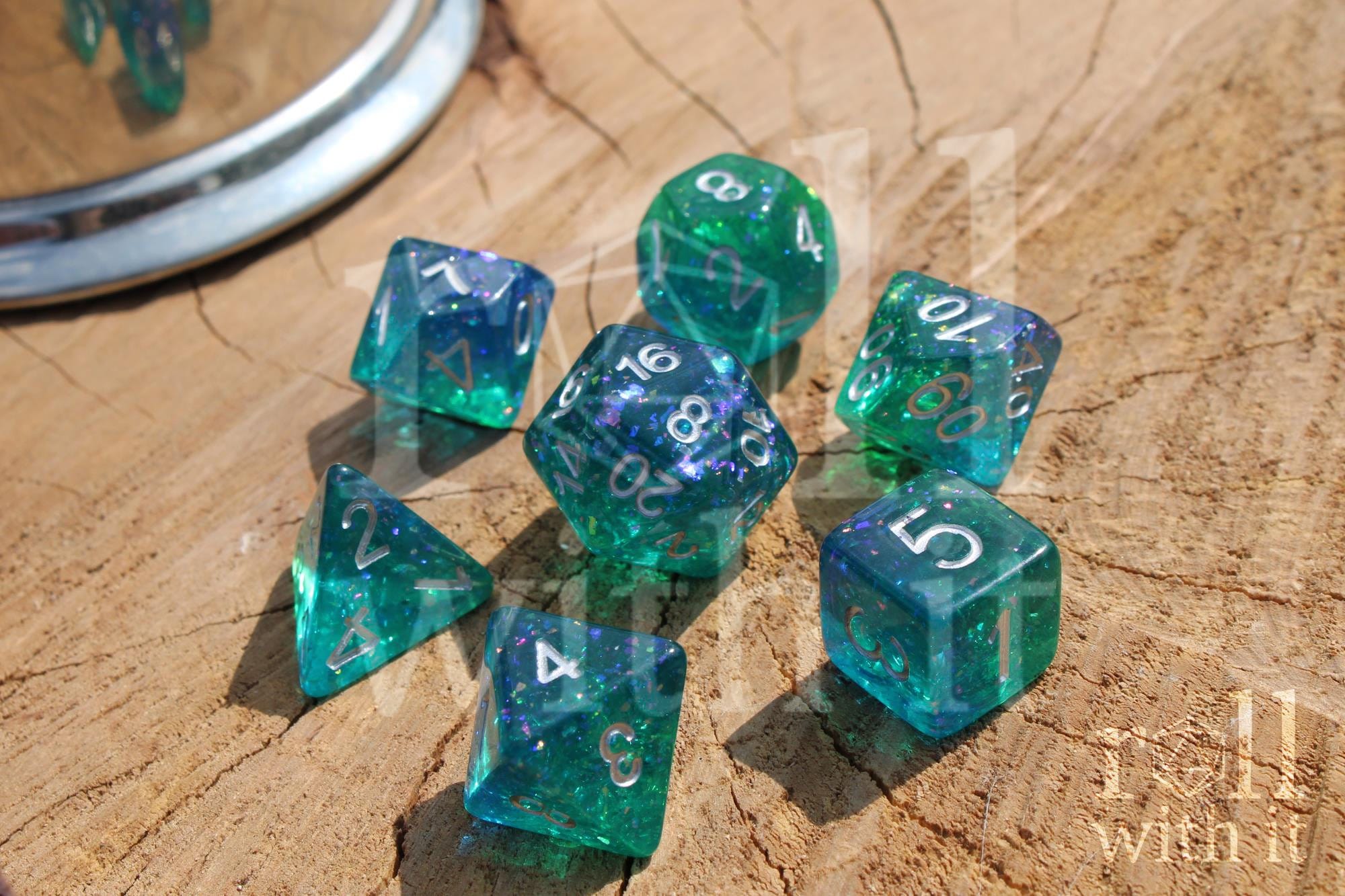 Set of glittery and shining blue and green polyhedral DND dice with silver leaf inside on a wooden surface
