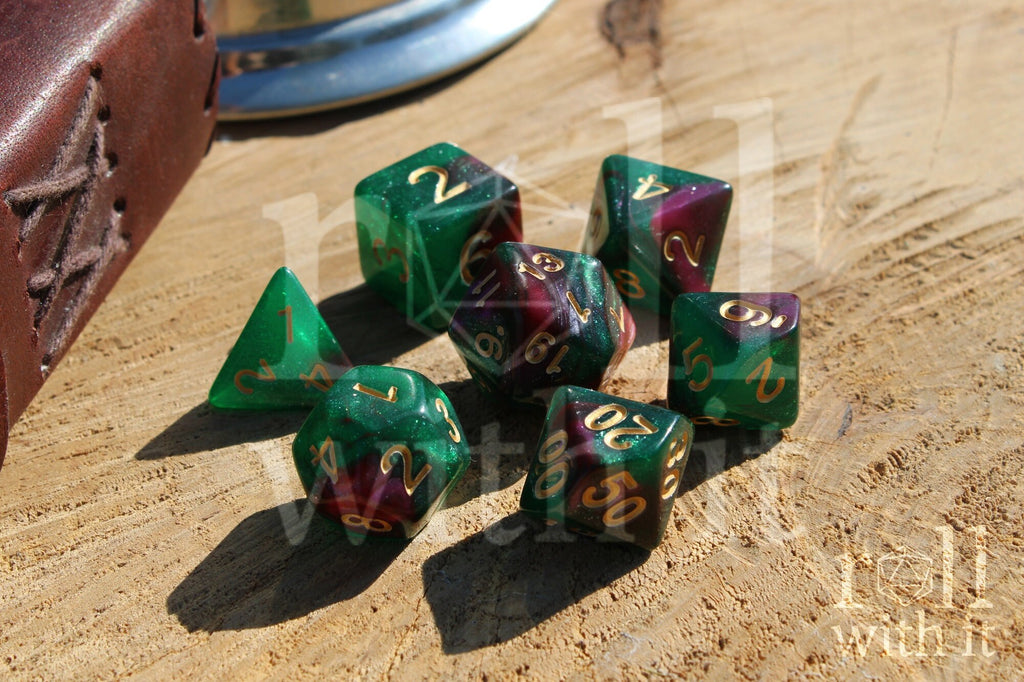 Set of glittery and shimmering green and purple polyhedral dice with gold numbers on a wooden surface