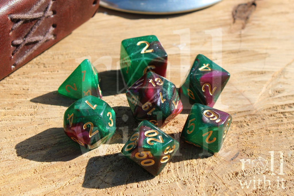 Set of glittery and shimmering green and purple polyhedral dice with gold numbers on a wooden surface