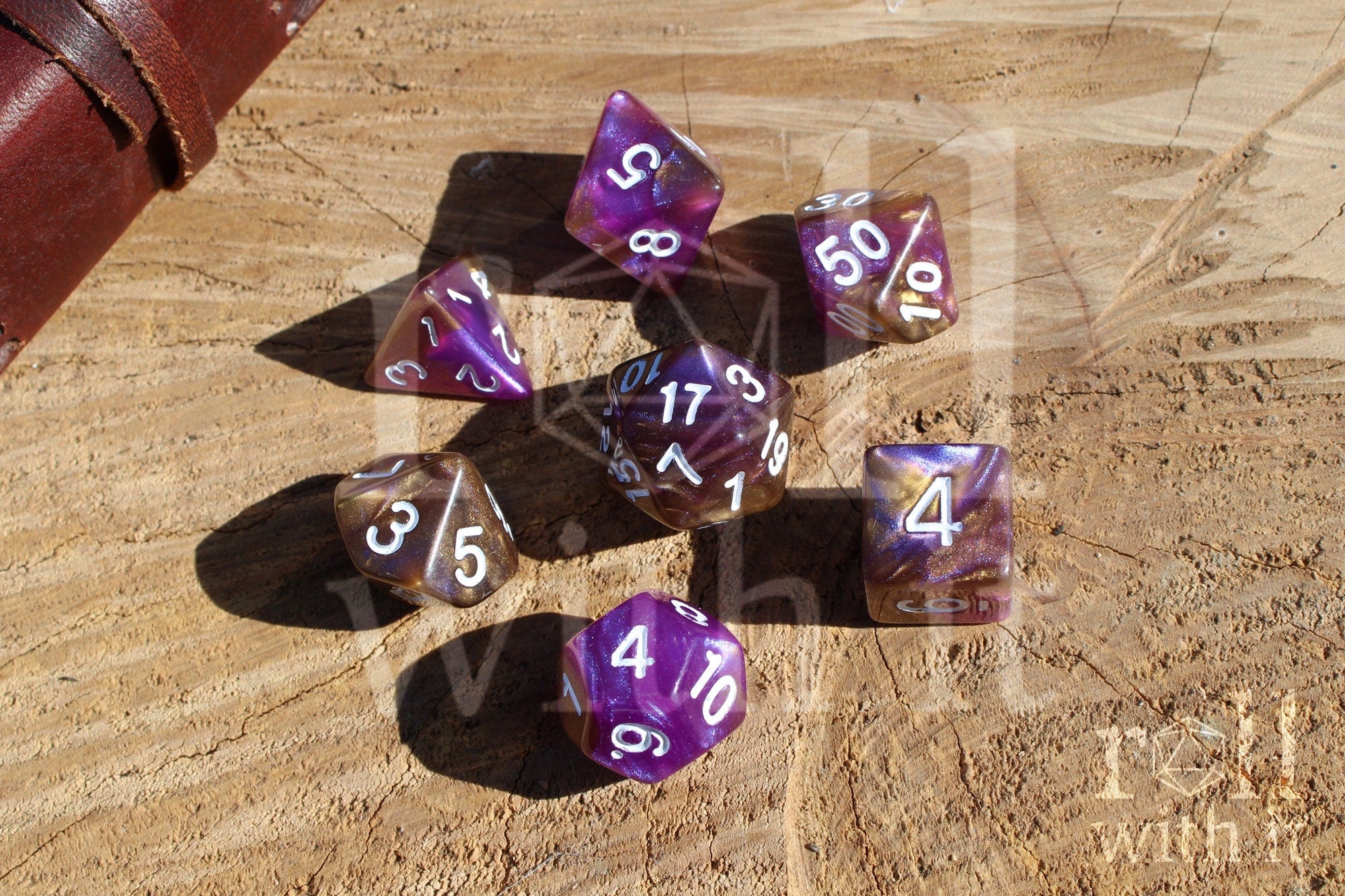 Purple and gold polyhedral roleplaying dice with white numbers on a wooden surface