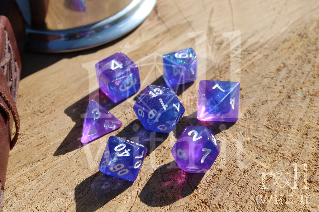Set of glittery indigo purple polyhedral DnD dice with white numbers on a wooden surface
