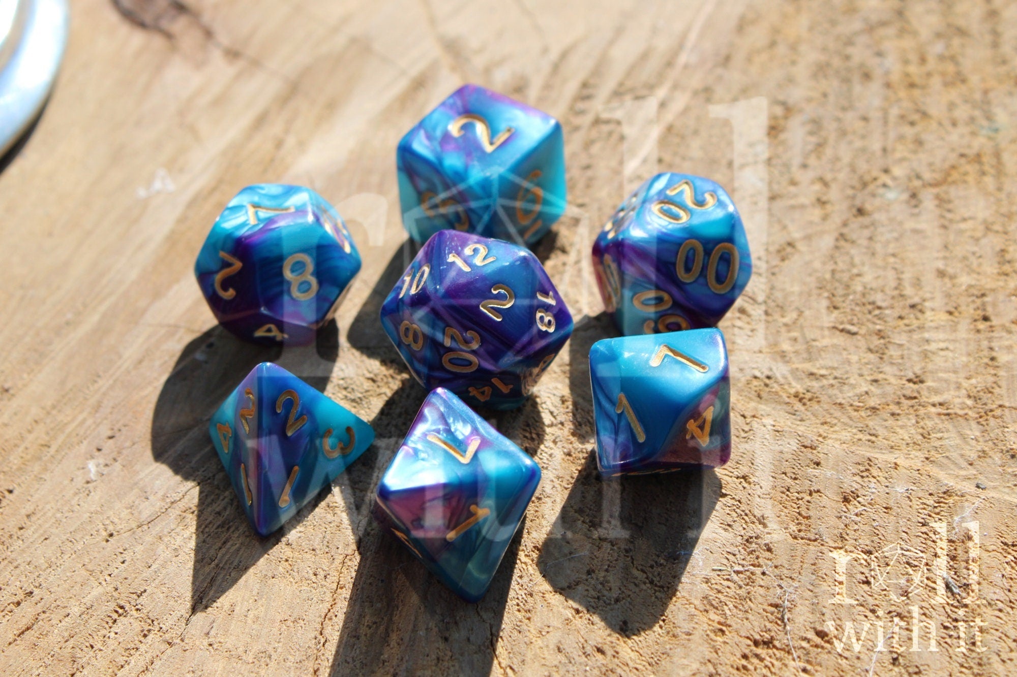 A set of colorful purple and blue polyhedral dice with golden numbers on a wooden surface