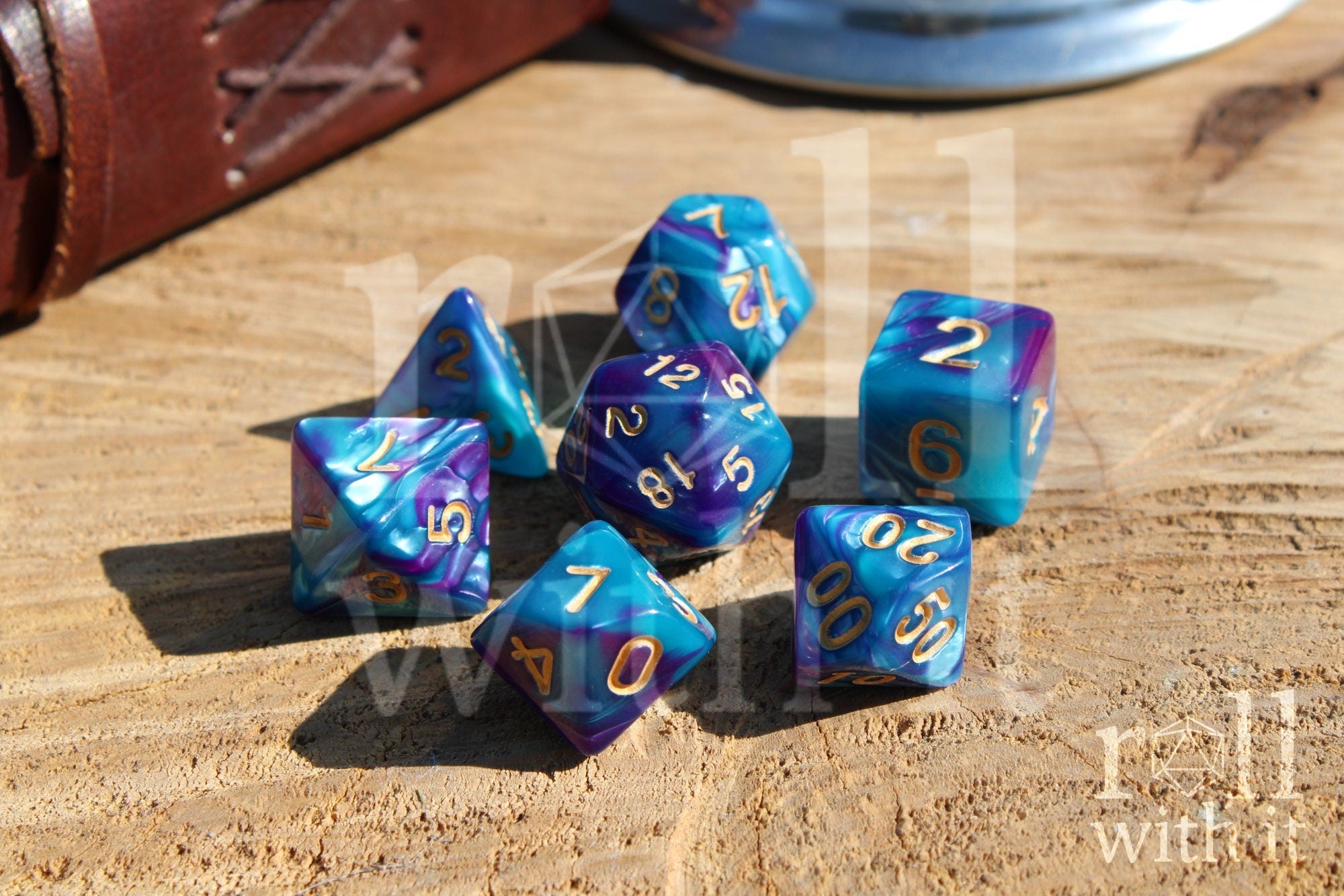 A set of colorful purple and blue polyhedral dice with golden numbers on a wooden surface
