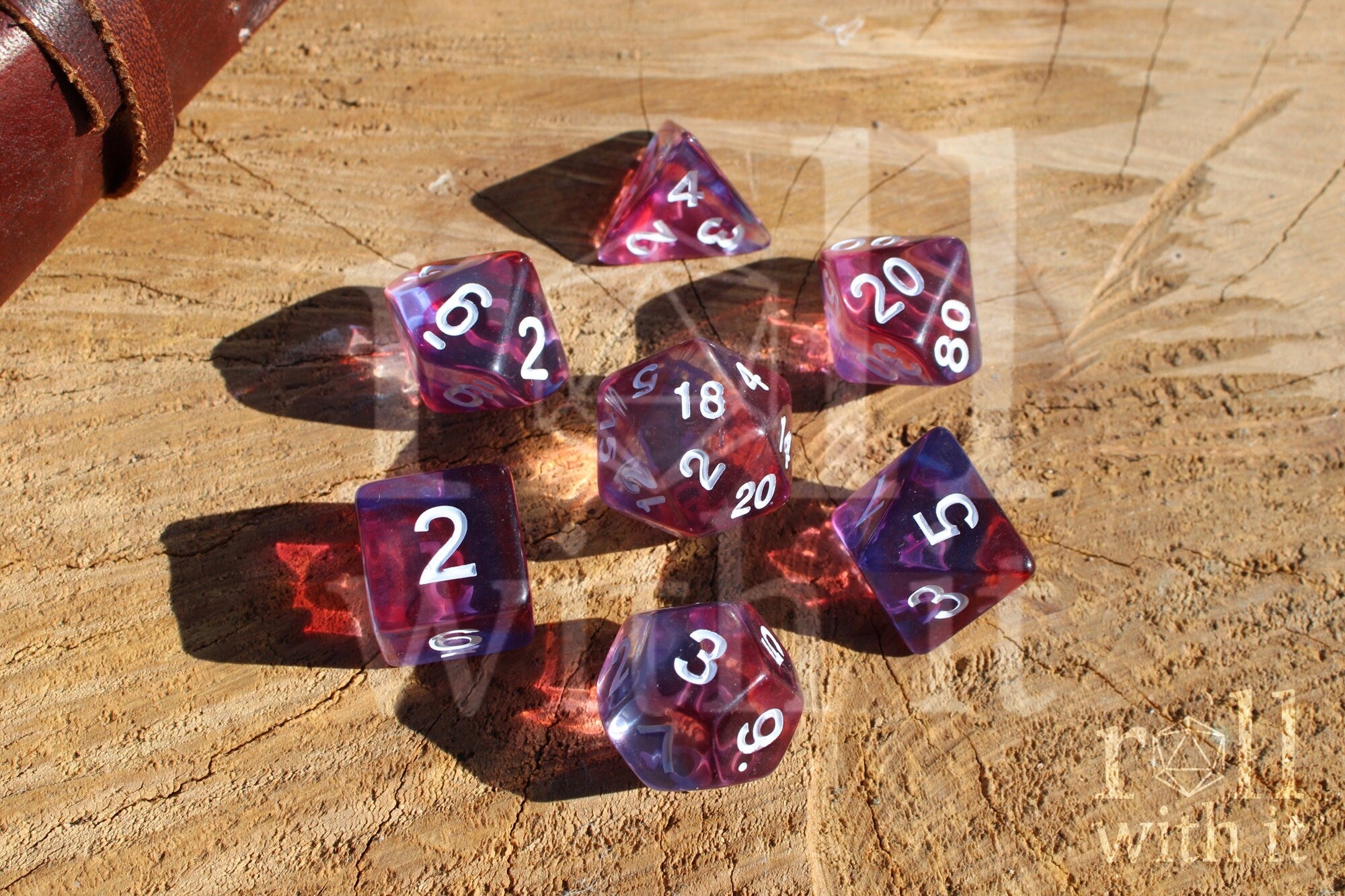 Set of clear purple and red dice with white numbers on a wooden surface