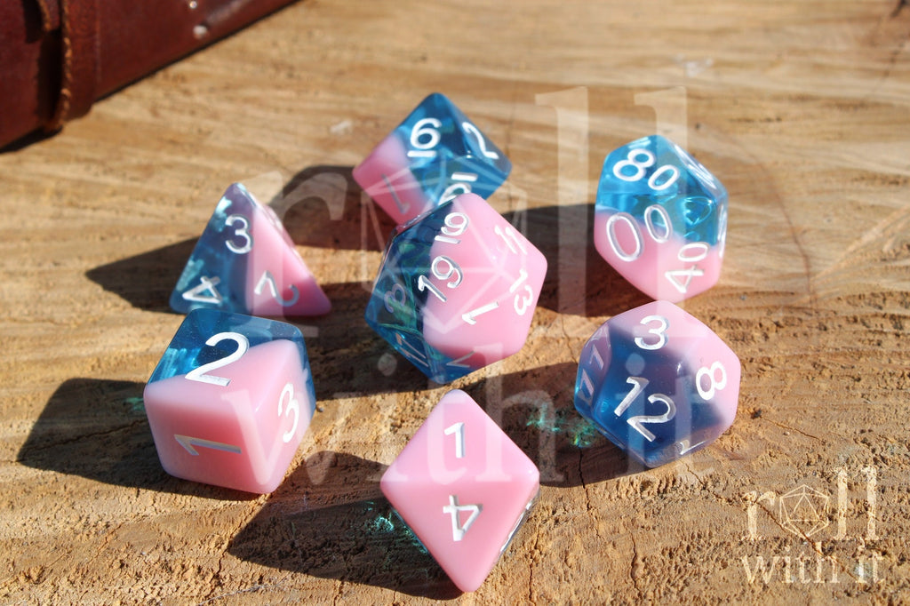 Set of bubblegum pink and clear blue polyhedral roleplaying dice on a wooden surface