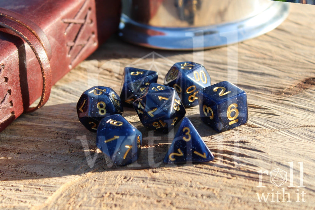Deep midnight blue polyhedral starry glittery DnD roleplaying dice with gold numbers on a wooden surface