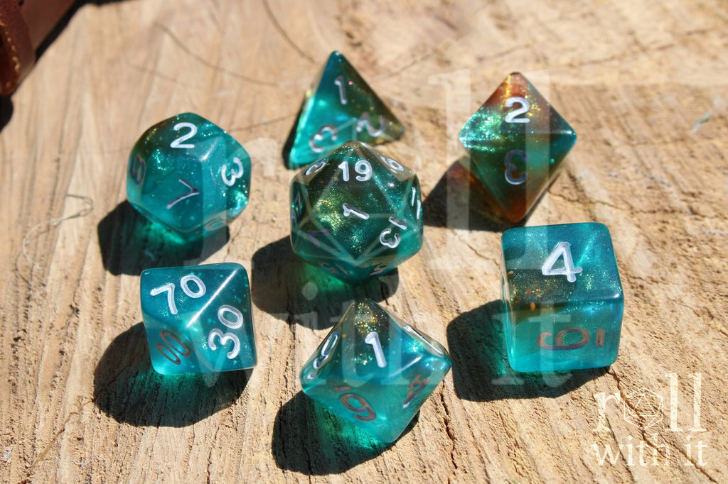 Set of turquoise blue and copper glittery polyhedral dice with white numbers on a wooden surface