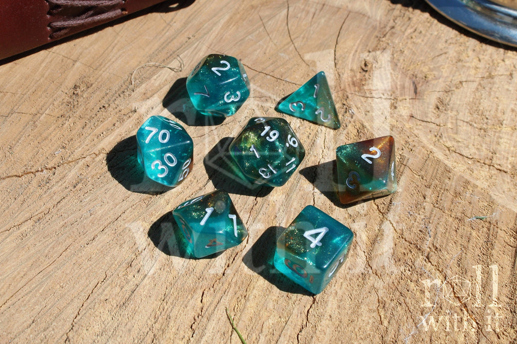 Set of blue and copper glittery polyhedral dice with white numbers on a wooden surface