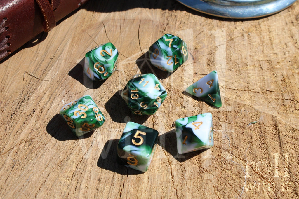 Set of swirling green and white polyhedral DND dice with gold numbers on a wooden surface