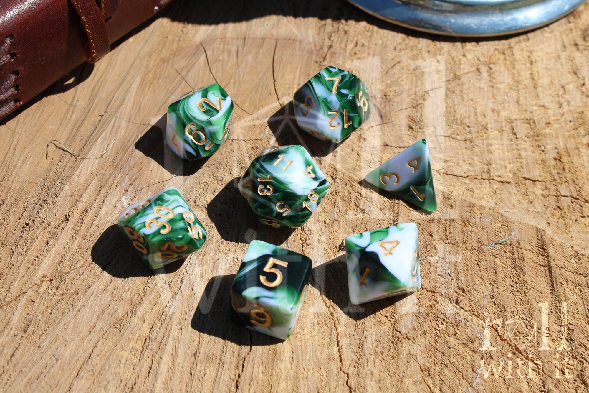 Set of swirling green and white polyhedral DND dice with gold numbers on a wooden surface