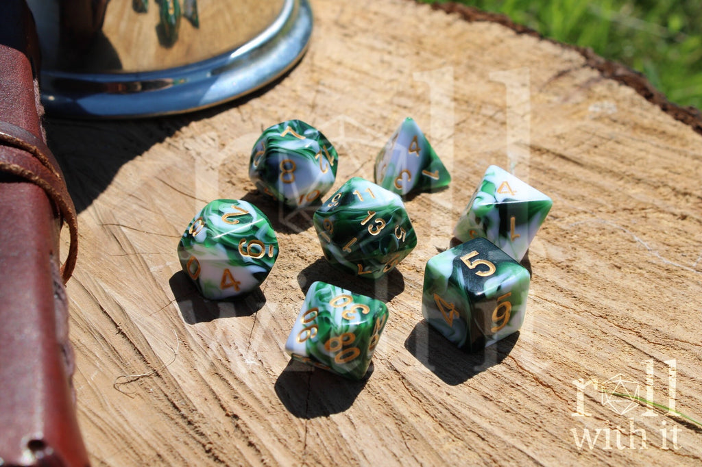 Set of green and white polyhedral dice with gold numbers on a wooden surface