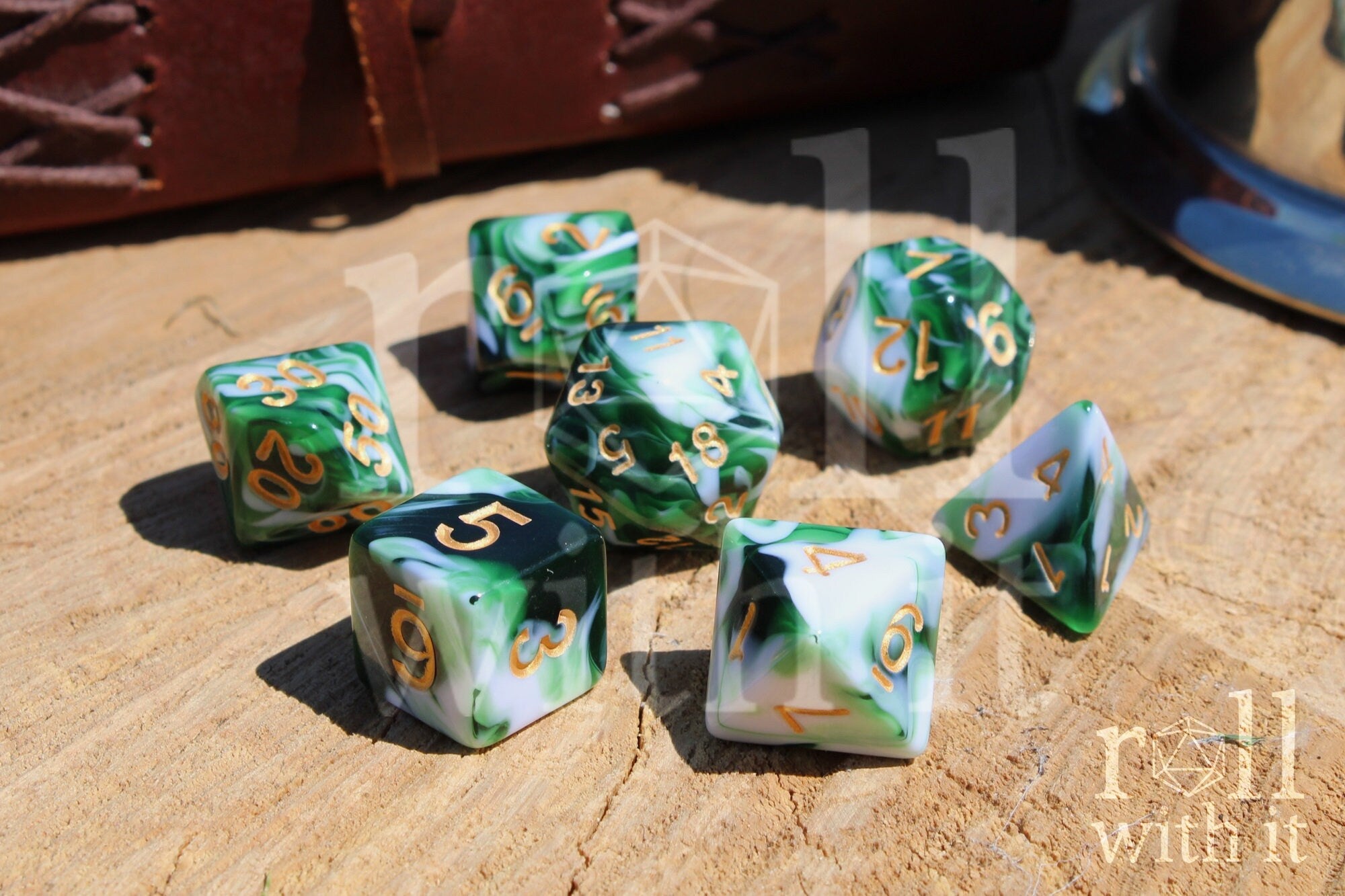 Set of green and white polyhedral dice with gold numbers on a wooden surface