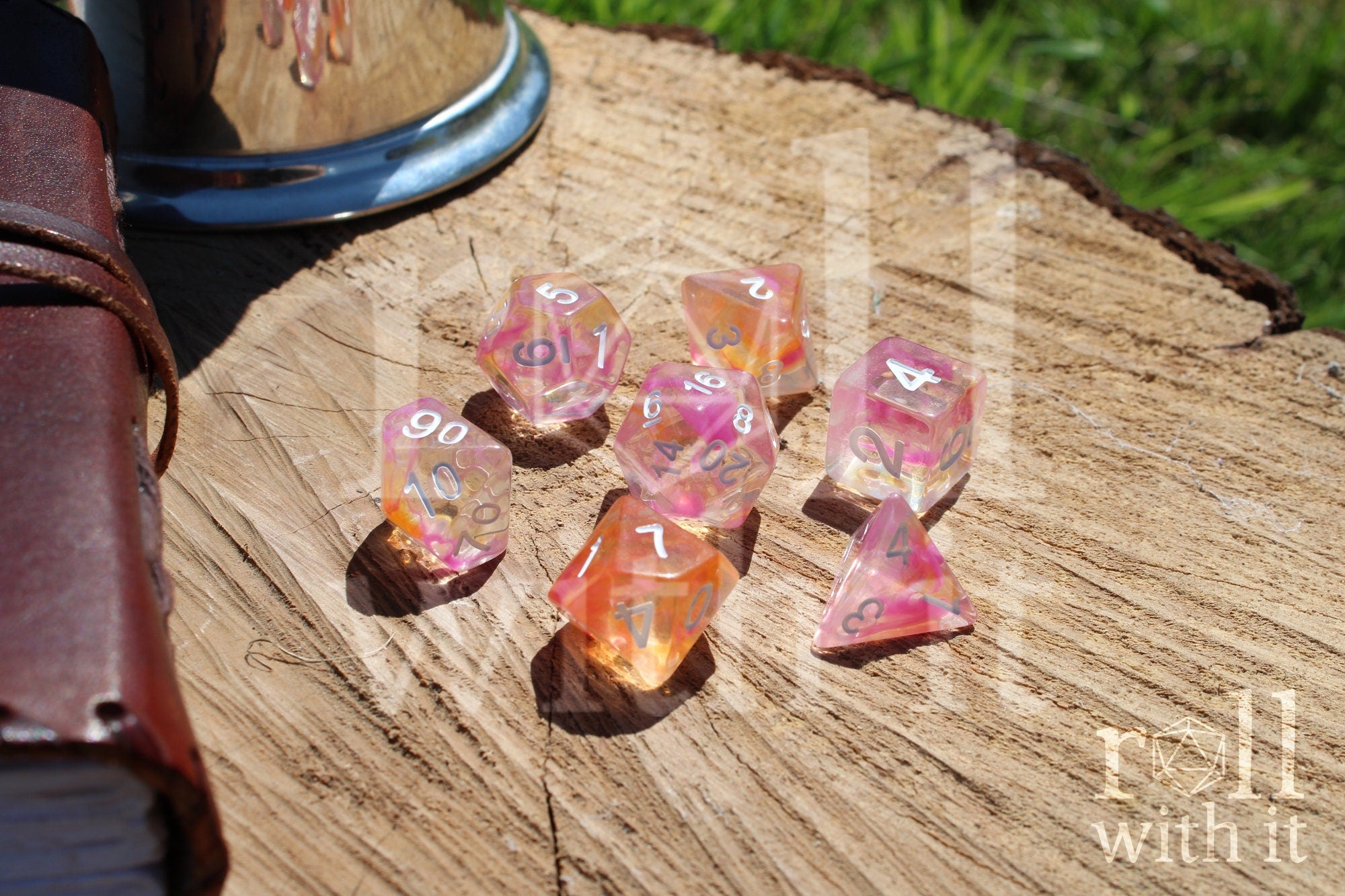 Set of colorful pink and orange clear polyhedral dice on a wooden surface