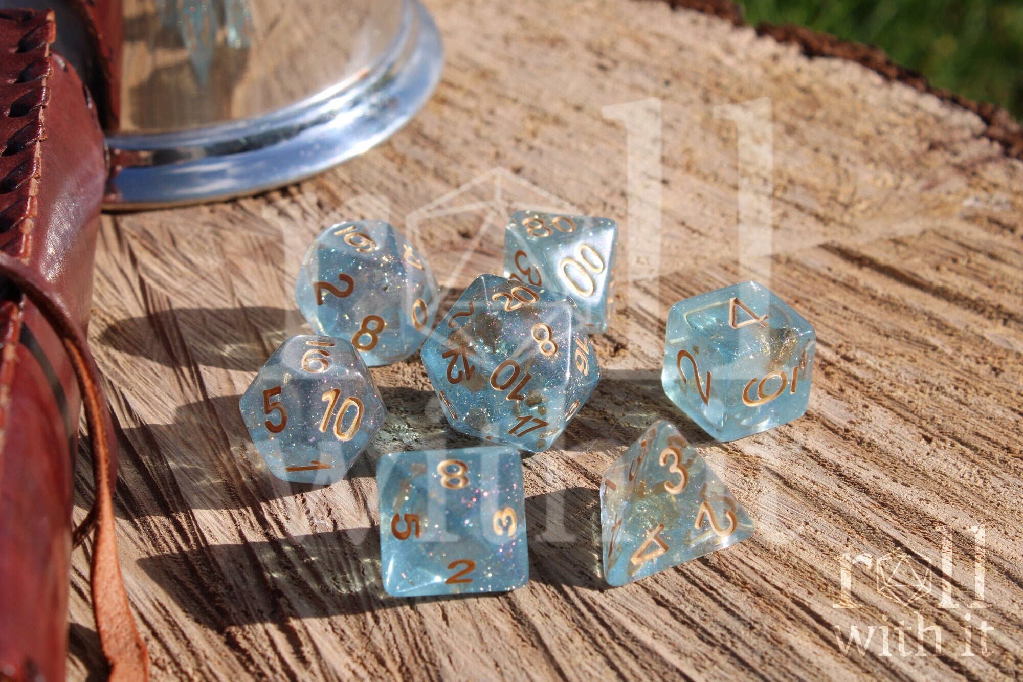 Set of clear blue and gold foil dice with gold numbers on a wooden surface
